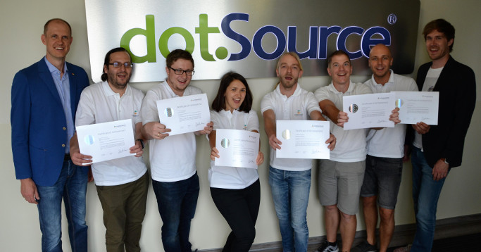 weiße poloshirts und zertifikate vor dotsource logo