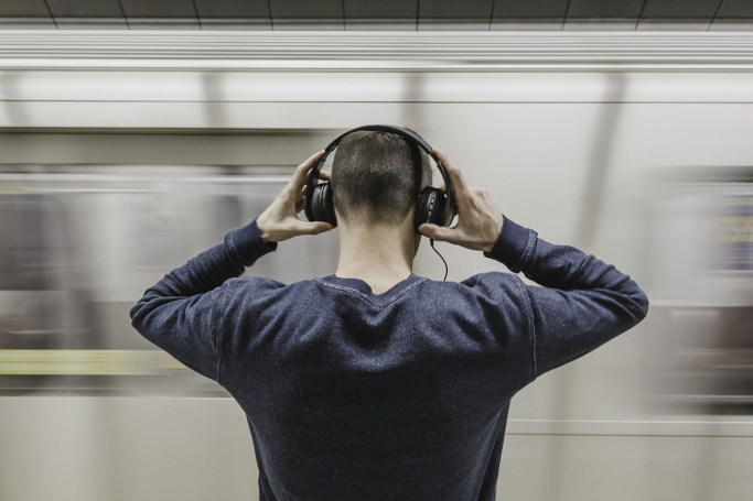 junger Mann in Underground-Station mit Kopfhöhrern