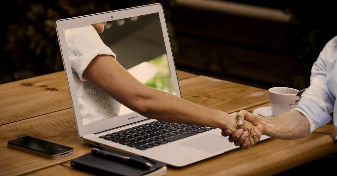 analogue Kundenbeziehung digital gestalten Handshake via Laptop Screen