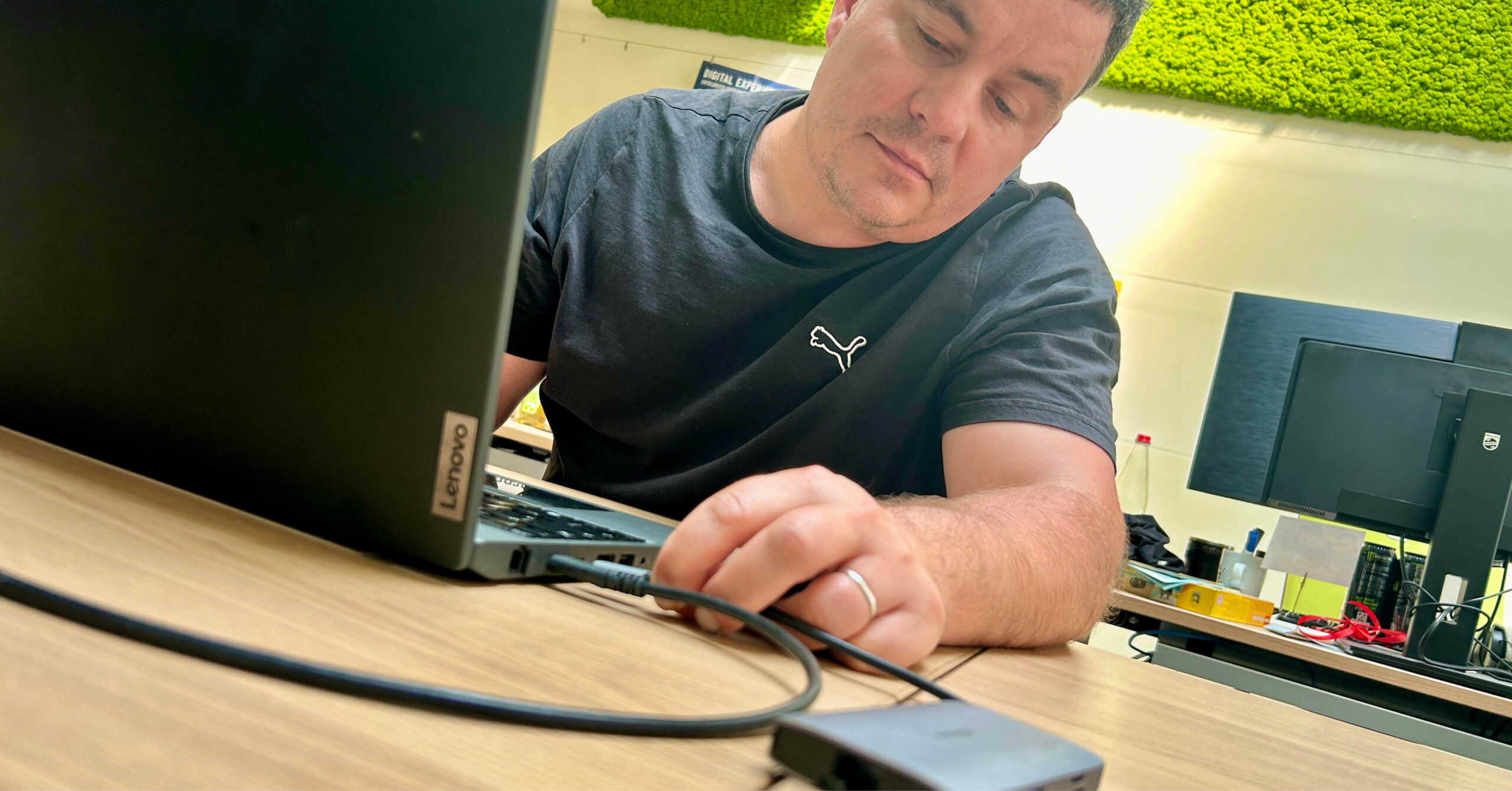 Nahaufnahme eines Mannes, der ein USB-C-Kabel in den Anschluss eines Computers einsteckt.
