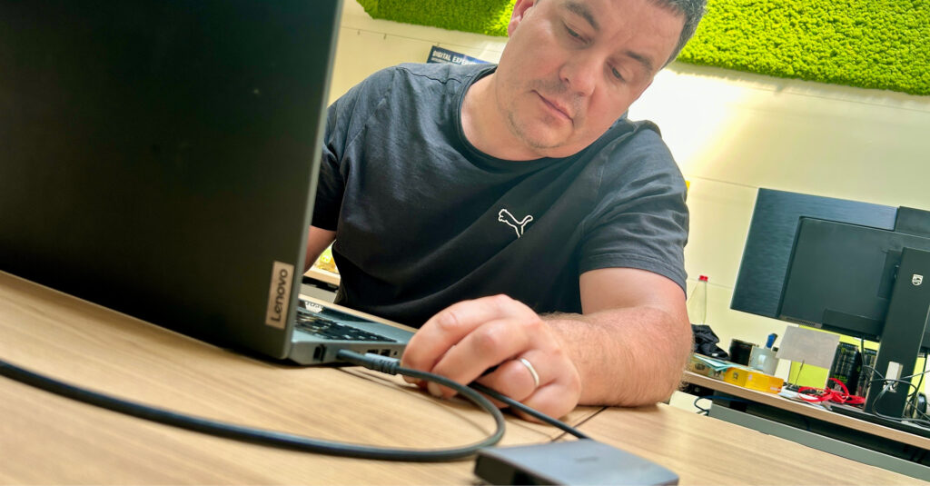 Nahaufnahme eines Mannes, der ein USB-C-Kabel in den Anschluss eines Computers einsteckt.