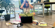 Eine Frau sitzt verzweifelt vor einem Laptop auf dem Boden und um sie herum herrscht Chaos.