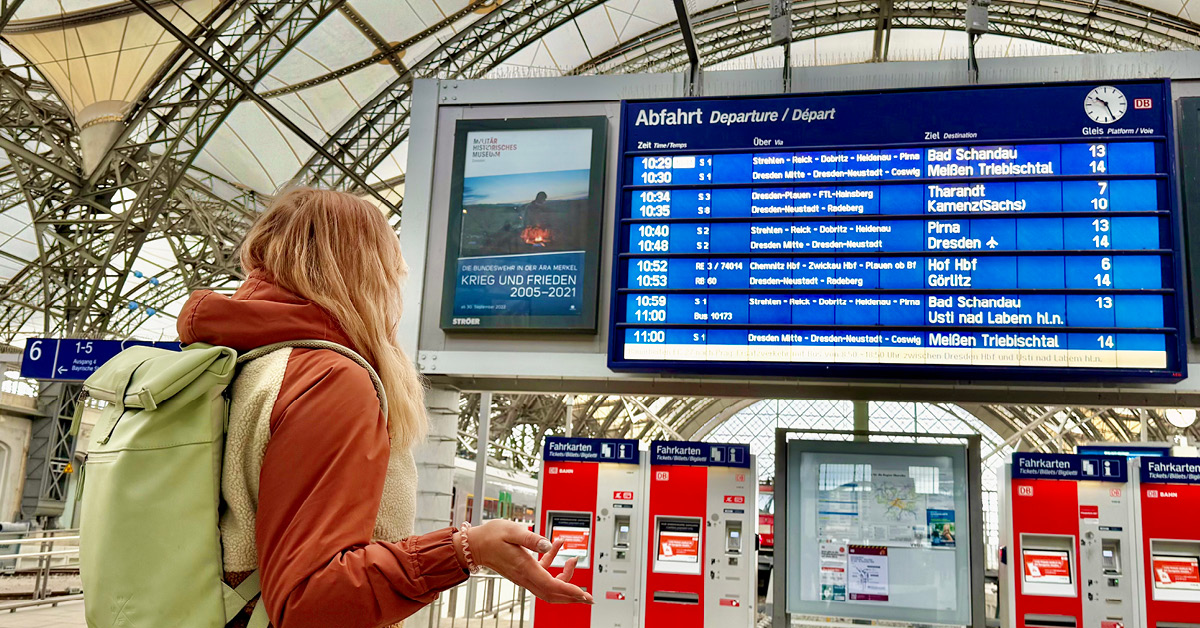 Eine Frau steht etwas verloren vor einer Bahnhofsanzeige.