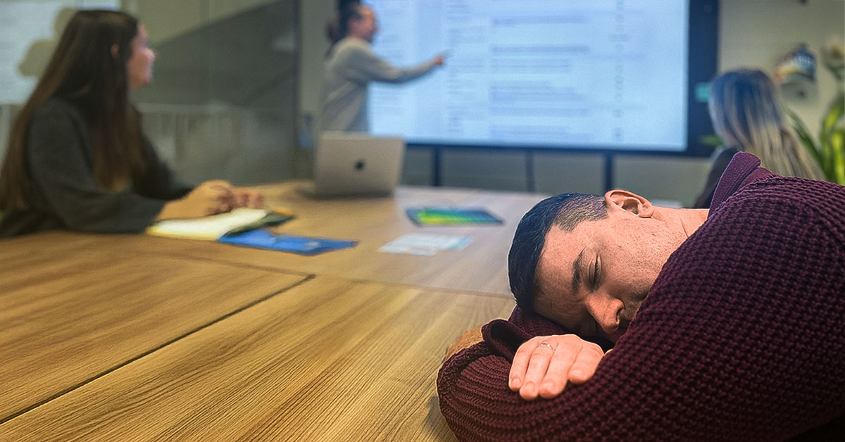 Ein Mann schläft während einer Weiterbildung auf dem Tisch.