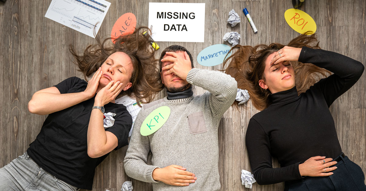 Drei Mitarbeiter liegt verzweifelt auf dem Boden. Sie sind umgeben von Papiermüll und ungenutzten Daten.