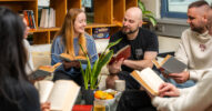 Sechs Menschen halten jeweils ein Buch und tauschen sich darüber aus.