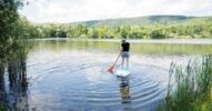Frau auf einem Stand-up-Paddle hält Balance und steuert – Metapher für KI‑Ads mit Leitplanken.