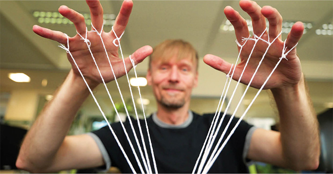 Mitarbeiter im Büro mit gespannten Fäden zwischen den Händen als Symbol für digitale Souveränität und Steuerungsfähigkeit in Unternehmen.