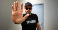 Symbolbild für KI-Sicherheit: Eine Person mit Security-Shirt hält die Hand als Stoppsignal in Richtung Kamera.